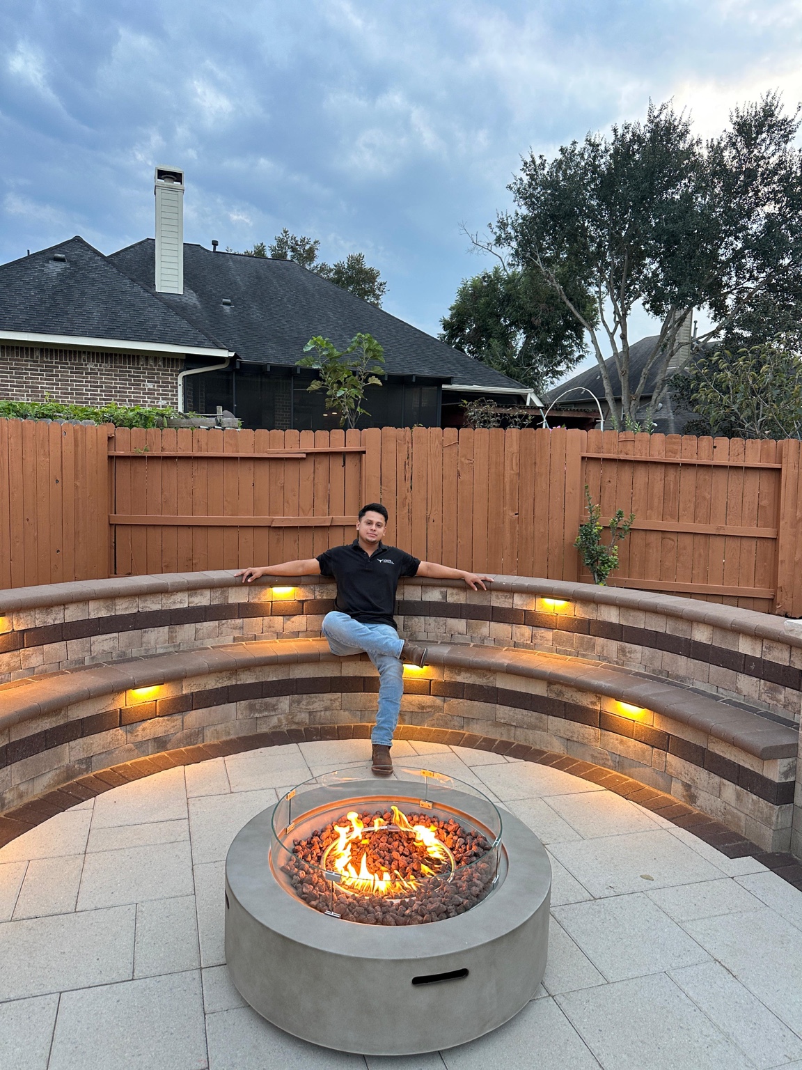 Cesar sitting next to a custom fire feature built by Longhorn Hardscape & Construction